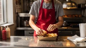 Jeune employé en cuisine de restauration rapide